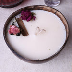 Small soy wax candle in a coconut bowl by Velarte, with a lit flame and natural coconut texture visible.