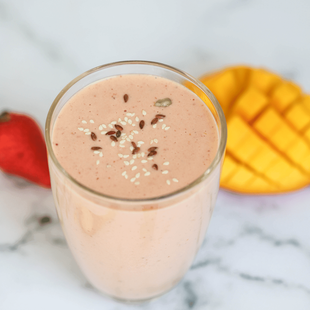 Vegan recipe book cover featuring a vibrant strawberry mango protein smoothie in a glass with fresh fruit and green leaves.