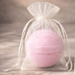 Pink Velarte bath bomb with a smooth spherical shape, designed for relaxing baths and colorful water effects.
