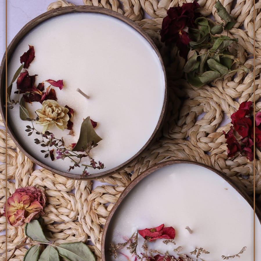Soy wax candle in a coconut bowl from Velarte, with a lit wick and natural coconut shell exterior.